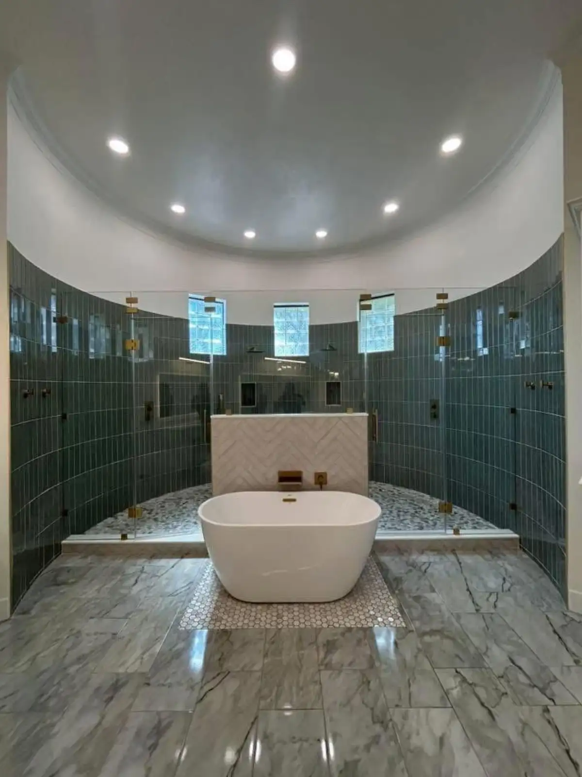 Luxury bathroom remodeling in Fort Worth featuring freestanding tub, curved blue-green tile wall, dual showers, and marble finishes by Water and Stone