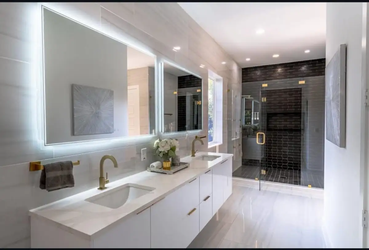 Luxury bathroom with dual floating vanity, LED mirrors, gold accents, and dark tile shower