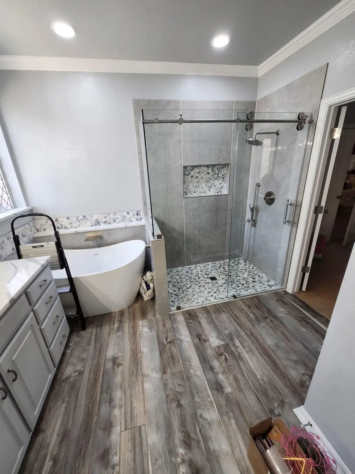 Bathroom design with a glass shower, freestanding tub, tile, and vanity