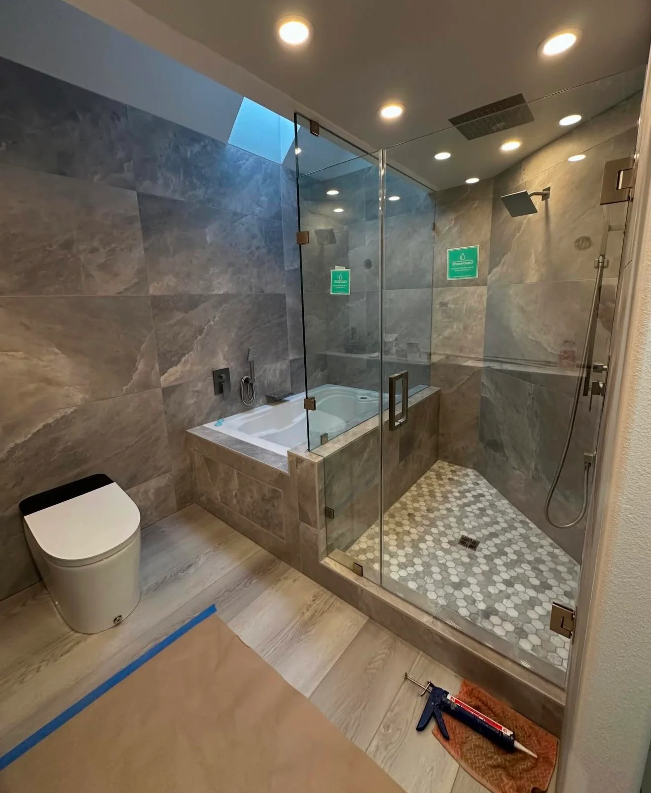 Bathroom renovation with a tiled glass shower, built-in bathtub, modern fixtures, and large-format wall tile