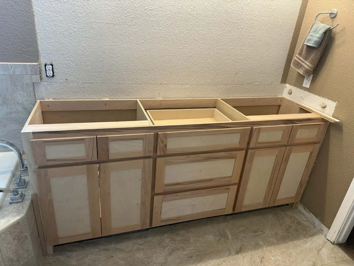 Double vanity cabinet being installed with raw wood frame before countertop and finishing