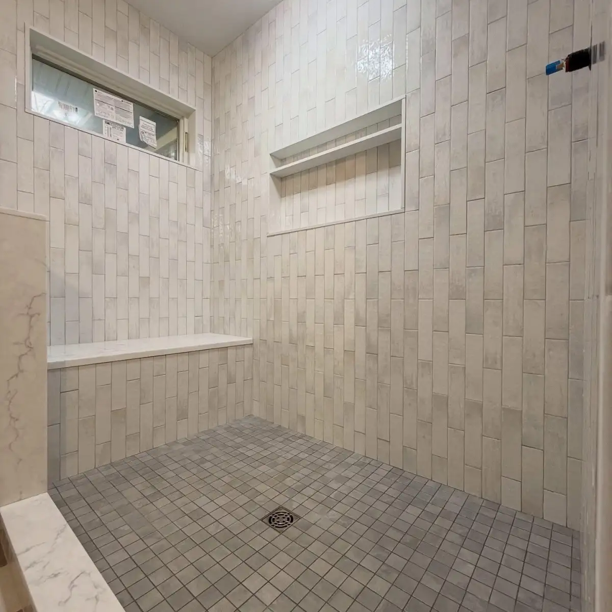 Vertical stacked zellige tile shower with bench and niches