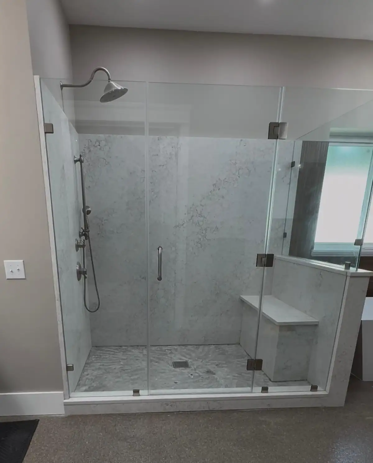 Large frameless glass walk-in shower with bench and stone walls in Arlington TX